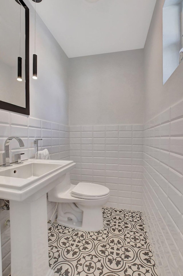 bathroom featuring tile patterned floors, toilet, and tile walls