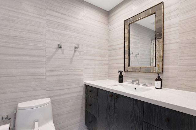 bathroom featuring vanity, tile walls, and toilet