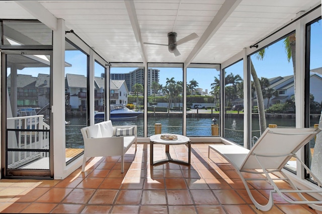 sunroom featuring beamed ceiling, ceiling fan, a water view, and a wealth of natural light