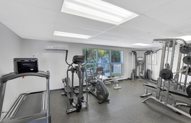 gym with a wall mounted air conditioner and a drop ceiling