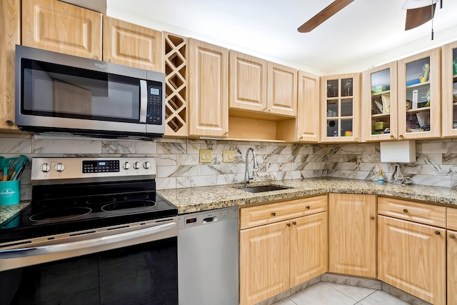 kitchen with sink, light tile patterned floors, appliances with stainless steel finishes, tasteful backsplash, and light stone counters