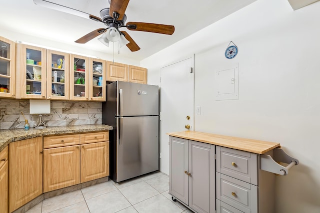 kitchen with light stone countertops, ceiling fan, stainless steel fridge, decorative backsplash, and light tile patterned flooring