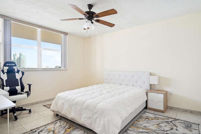 tiled bedroom with ceiling fan and a textured ceiling