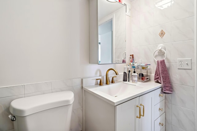 bathroom with vanity, tile walls, and toilet