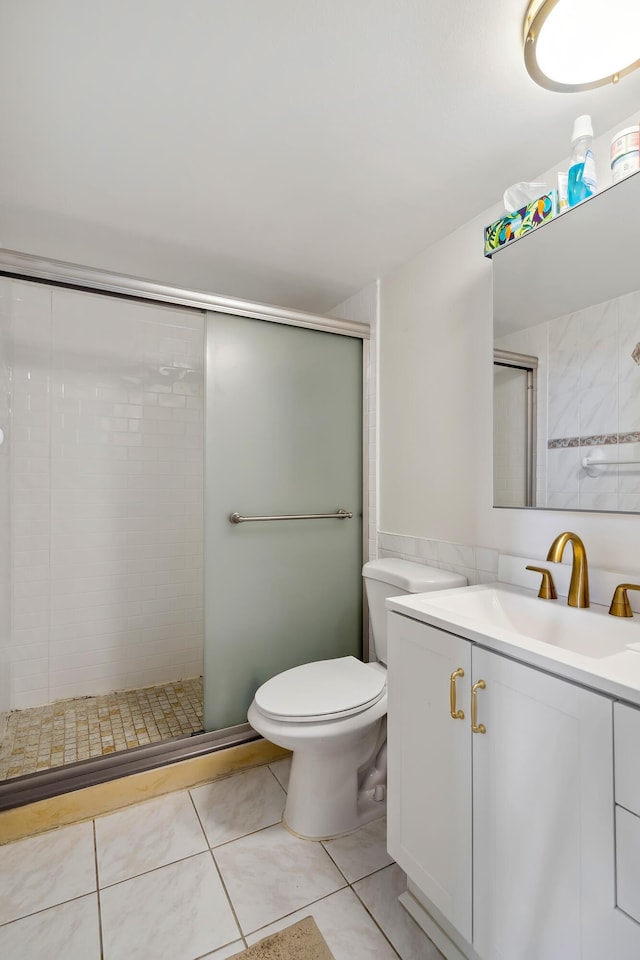 bathroom featuring toilet, vanity, tile patterned floors, and a shower with shower door