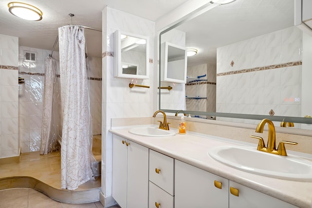 bathroom featuring shower / bathtub combination with curtain, tile patterned flooring, vanity, and tile walls