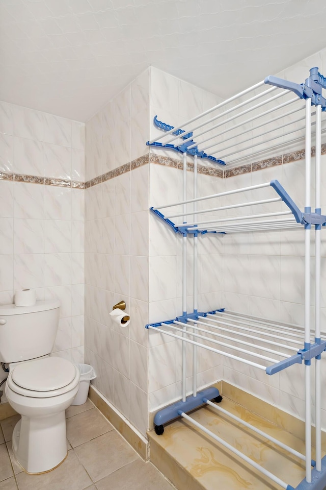 bathroom with tile patterned floors, toilet, and tile walls