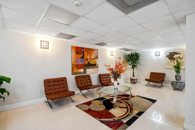 living area with a drop ceiling and tile patterned flooring