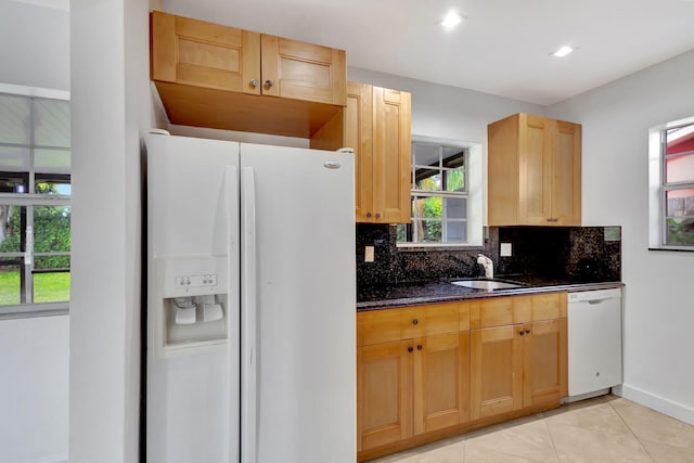 kitchen featuring sink, white appliances, light tile patterned flooring, decorative backsplash, and dark stone counters