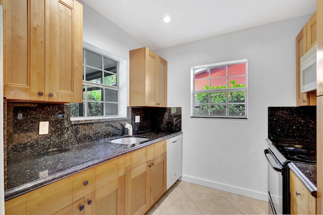 kitchen featuring sink, white appliances, light tile patterned floors, dark stone countertops, and decorative backsplash