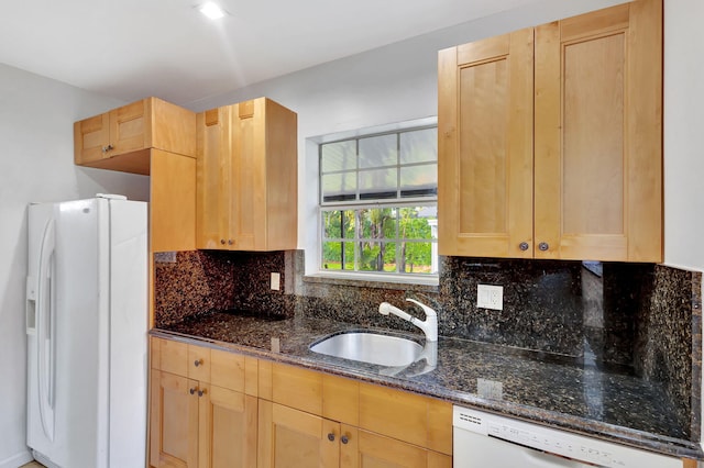 kitchen with sink, white appliances, backsplash, dark stone counters, and light brown cabinets