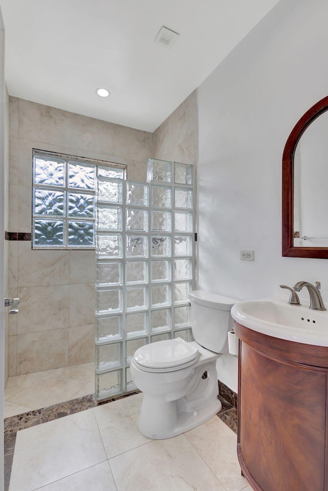 bathroom with vanity, toilet, and tiled shower