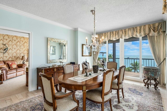 dining room with a water view, crown molding, light hardwood / wood-style flooring, a textured ceiling, and a notable chandelier