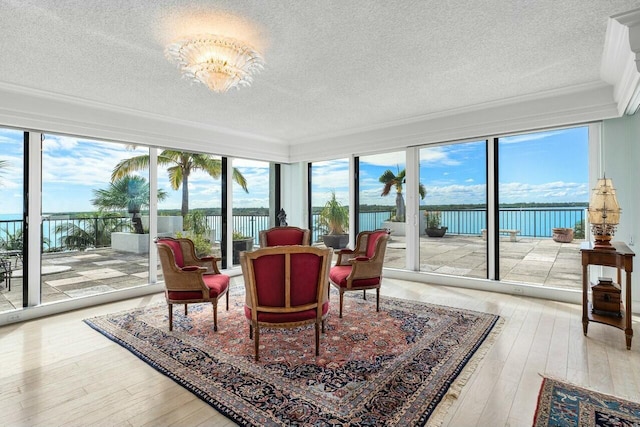 sunroom / solarium featuring a water view and a notable chandelier