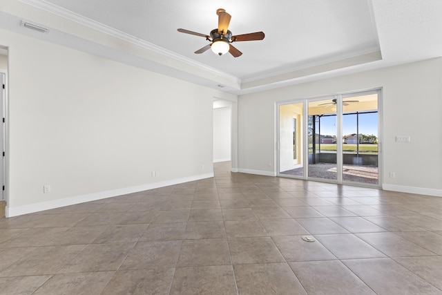 empty room with light tile patterned flooring, ceiling fan, ornamental molding, and a raised ceiling