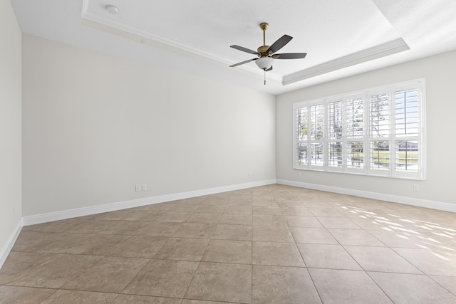 tiled spare room with a raised ceiling, ornamental molding, and ceiling fan