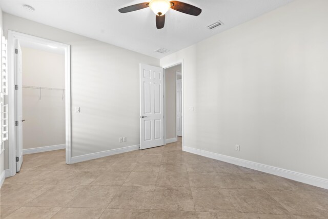 unfurnished bedroom with a spacious closet, ceiling fan, and a closet