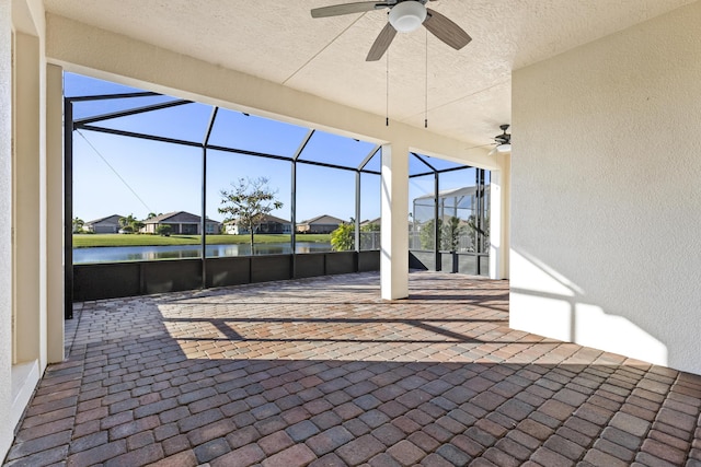 view of patio / terrace featuring a water view, ceiling fan, and glass enclosure