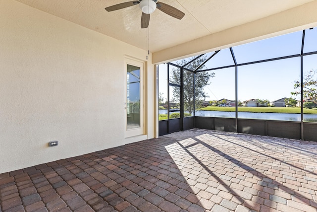 sunroom with ceiling fan and a water view