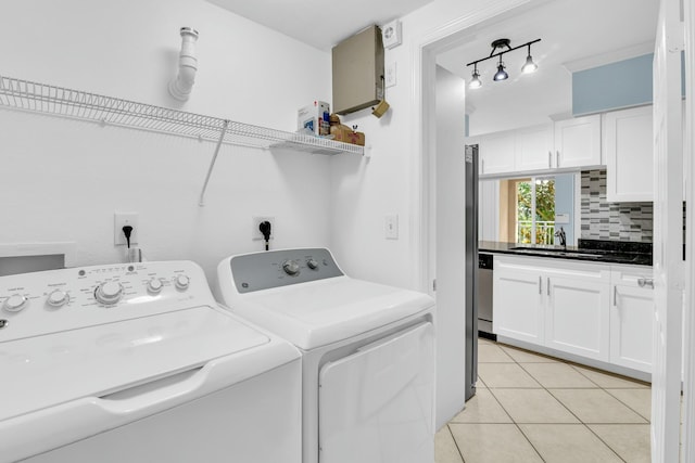 clothes washing area featuring washer and clothes dryer, sink, track lighting, and light tile patterned flooring