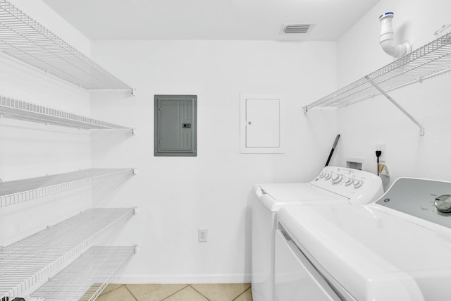 washroom with washing machine and dryer, light tile patterned floors, and electric panel