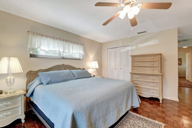 bedroom featuring a textured ceiling, dark parquet floors, a closet, and ceiling fan