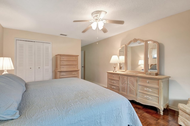 bedroom with dark parquet flooring, a textured ceiling, a closet, and ceiling fan