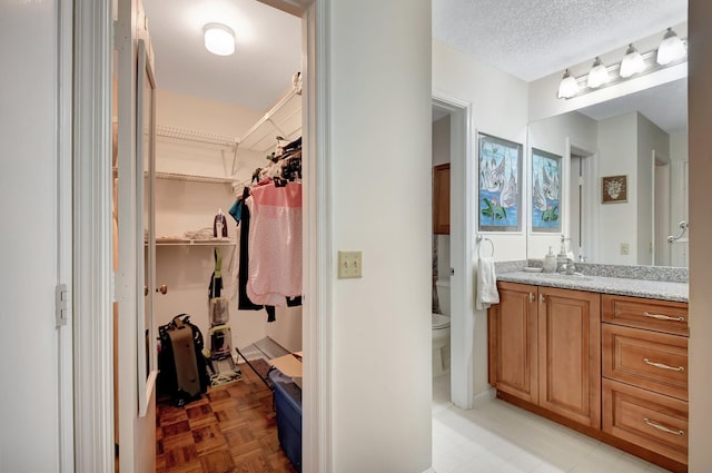 bathroom with vanity, parquet floors, a textured ceiling, and toilet