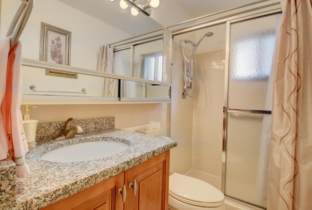 bathroom with a shower with door, vanity, and toilet