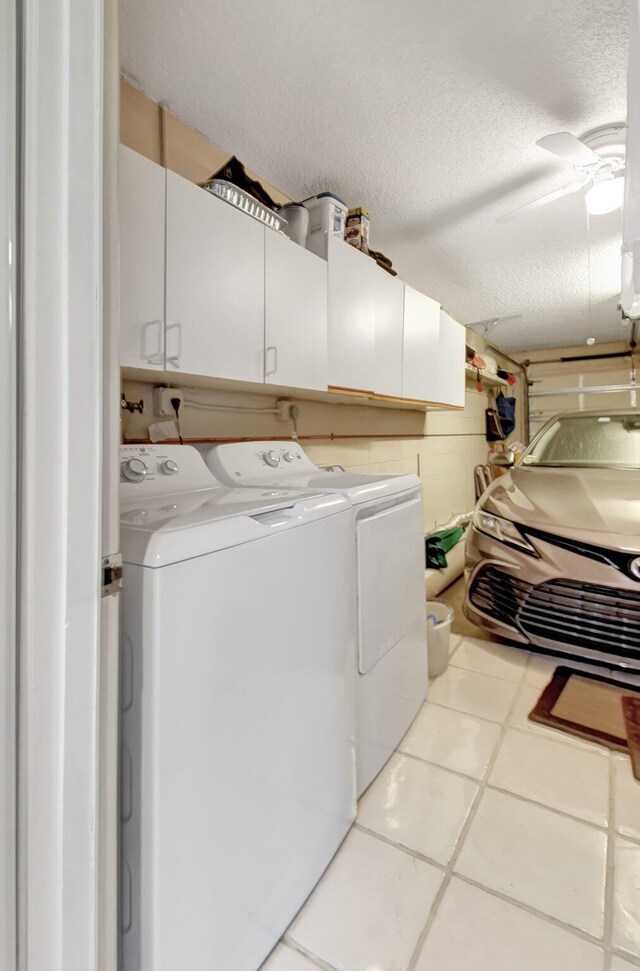 laundry area with cabinets, separate washer and dryer, light tile patterned floors, and a textured ceiling