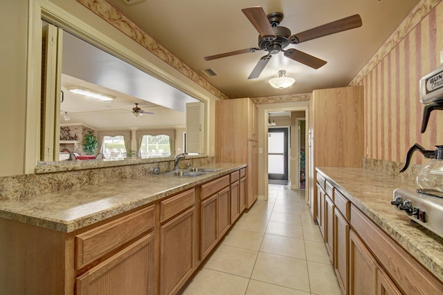 kitchen featuring light tile patterned floors, a ceiling fan, a sink, and wallpapered walls