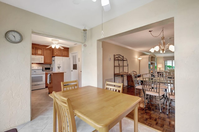 dining space featuring crown molding and ceiling fan with notable chandelier