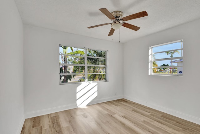 unfurnished room featuring a textured ceiling, light wood-type flooring, and a wealth of natural light