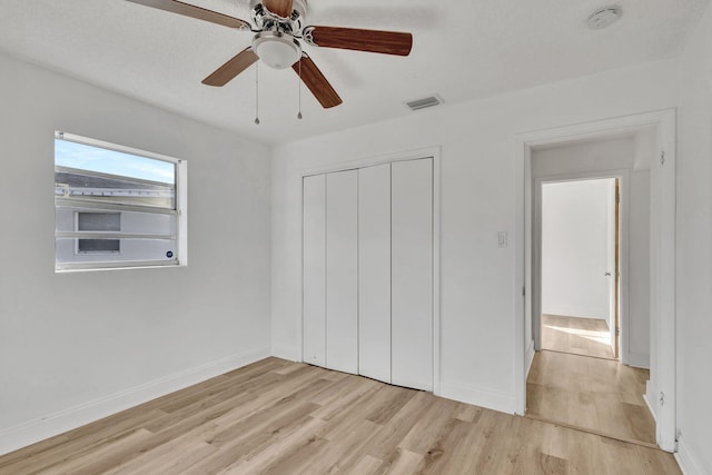 unfurnished bedroom with a textured ceiling, a closet, light hardwood / wood-style floors, and ceiling fan