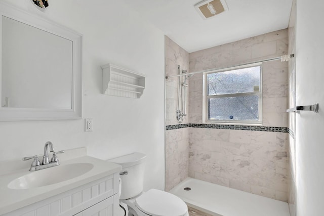 bathroom featuring vanity, toilet, and tiled shower