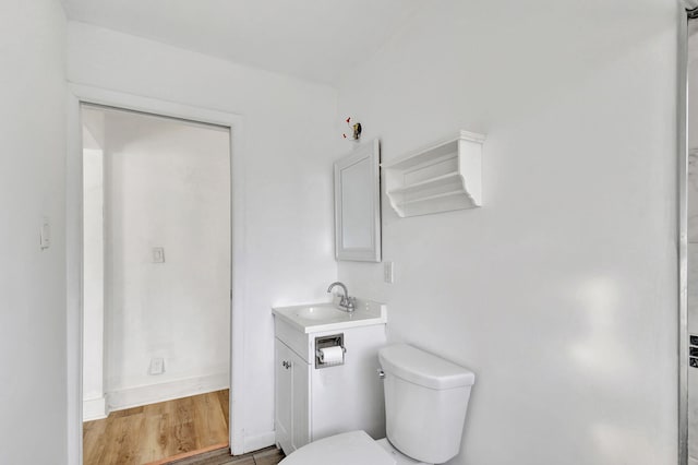 bathroom with hardwood / wood-style floors, vanity, and toilet