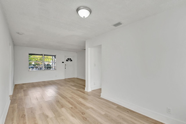 empty room featuring a textured ceiling and light hardwood / wood-style flooring