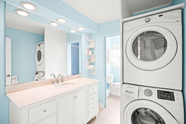 laundry area featuring sink, light tile patterned floors, and stacked washing maching and dryer