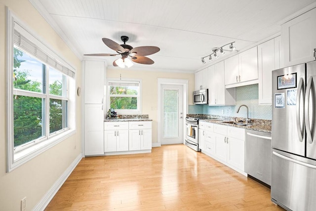 kitchen with stone counters, sink, light wood-type flooring, white cabinetry, and stainless steel appliances