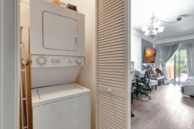 clothes washing area with ornamental molding, stacked washer / drying machine, a chandelier, and light hardwood / wood-style flooring