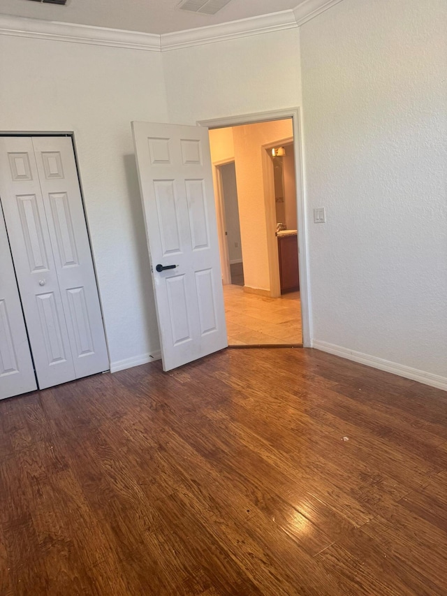 unfurnished bedroom with ornamental molding, dark wood-type flooring, and a closet