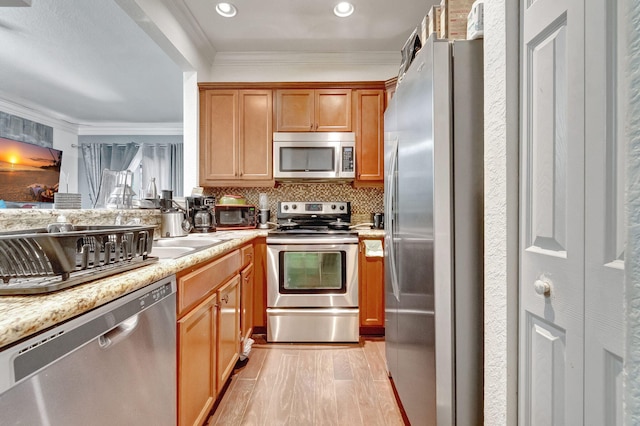 kitchen featuring light stone countertops, backsplash, light wood-type flooring, appliances with stainless steel finishes, and ornamental molding