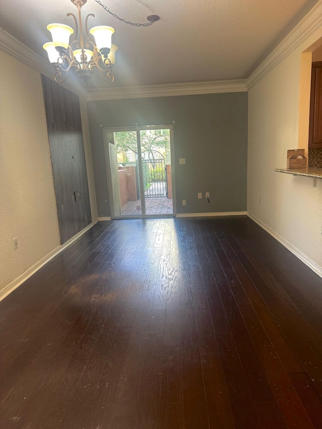 empty room with crown molding, dark hardwood / wood-style floors, and a notable chandelier