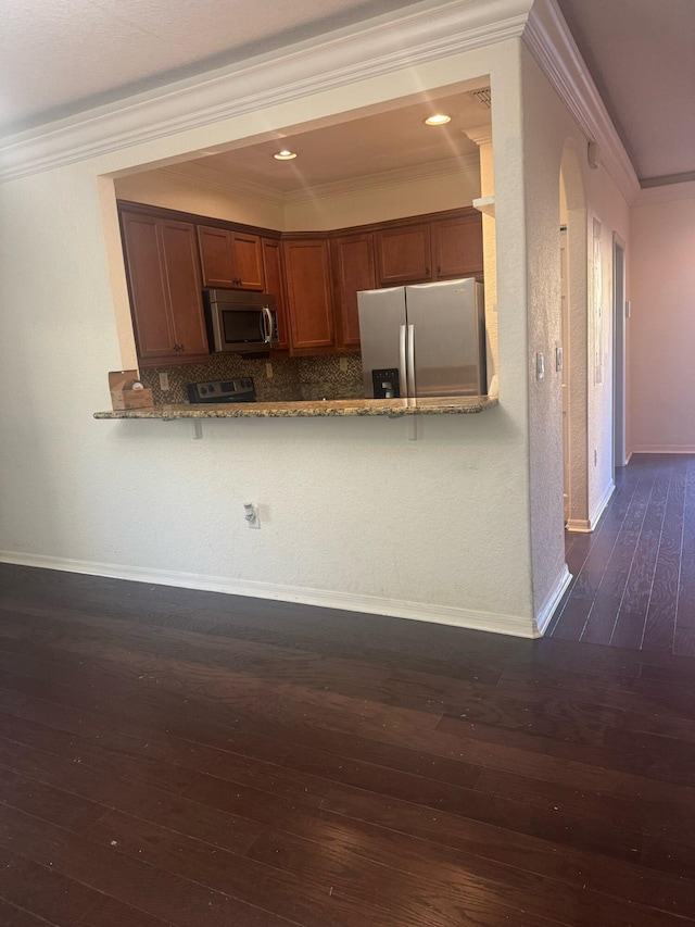 kitchen featuring light stone counters, ornamental molding, stainless steel appliances, and kitchen peninsula