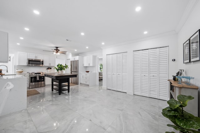 kitchen featuring light stone countertops, sink, stainless steel appliances, white cabinets, and ornamental molding