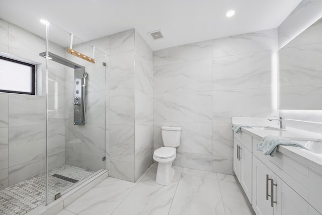 bathroom with a shower with door, vanity, tile walls, and toilet