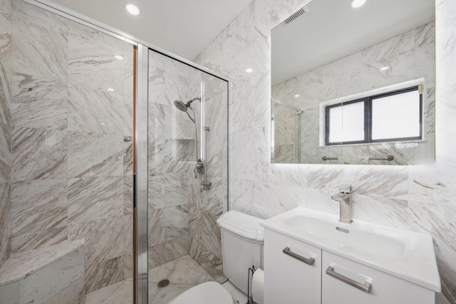 bathroom featuring vanity, toilet, tiled shower, and tile walls