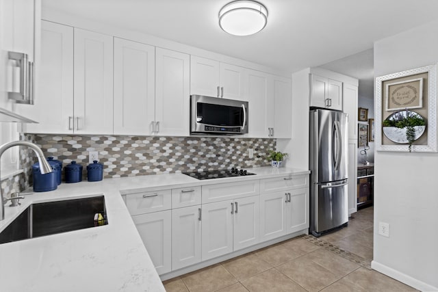 kitchen with white cabinets, sink, light stone countertops, light tile patterned floors, and stainless steel appliances