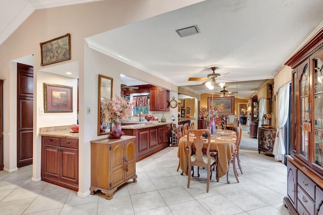 dining room featuring lofted ceiling, crown molding, ceiling fan, and light tile patterned floors