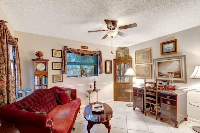 living area featuring ceiling fan, light tile patterned flooring, and a textured ceiling